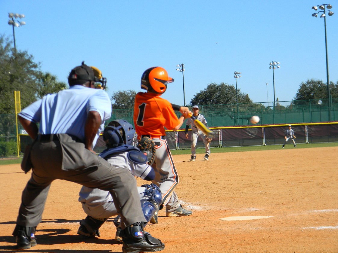 Babe Ruth Youth baseball game, batter swinging at a pitched ball, catcher and umpire behind the batter. A ouple of fielders are ready to field the potential hit. 