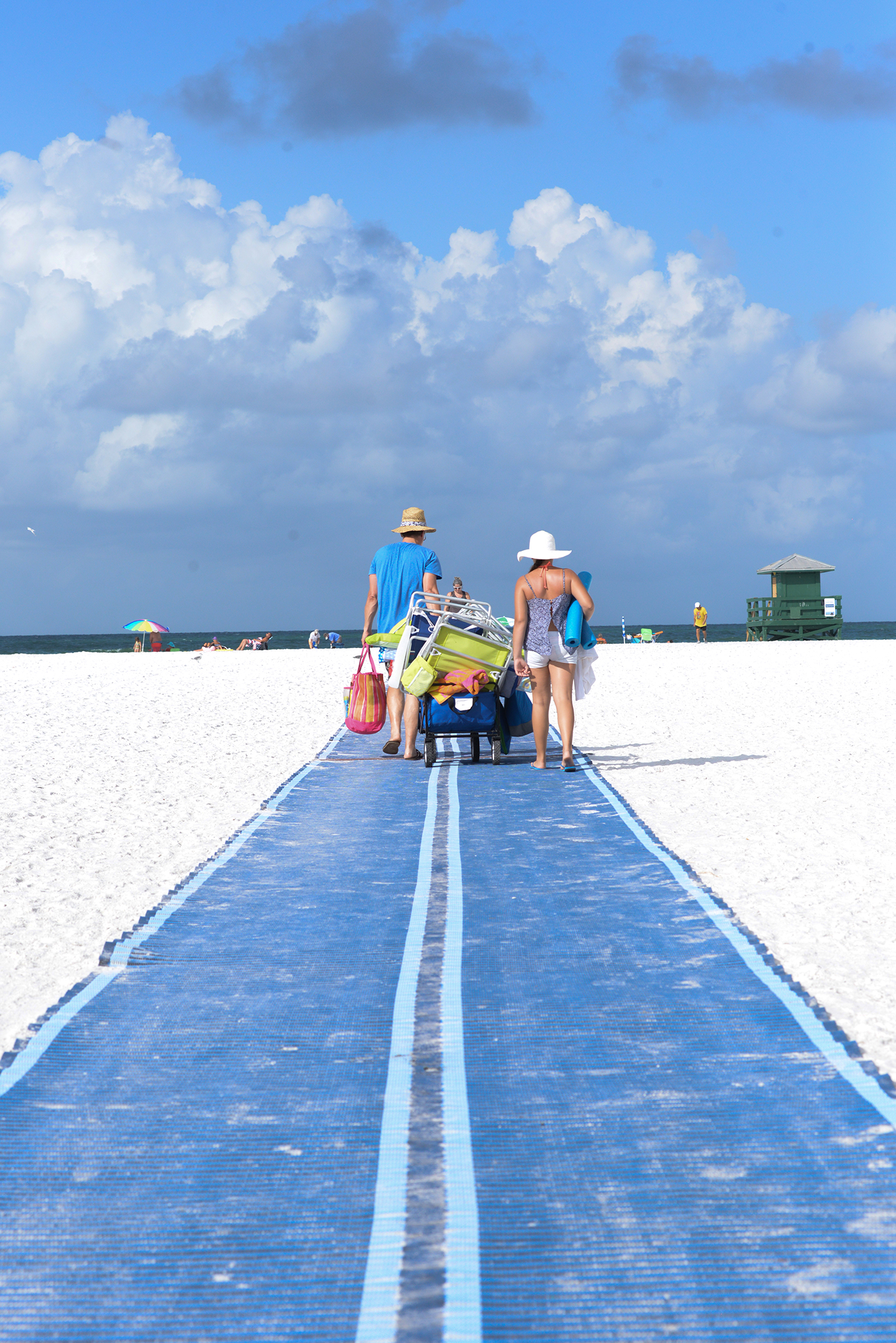 Couple using the new Mobi Mat to pull a wagon onto Siesta Beach